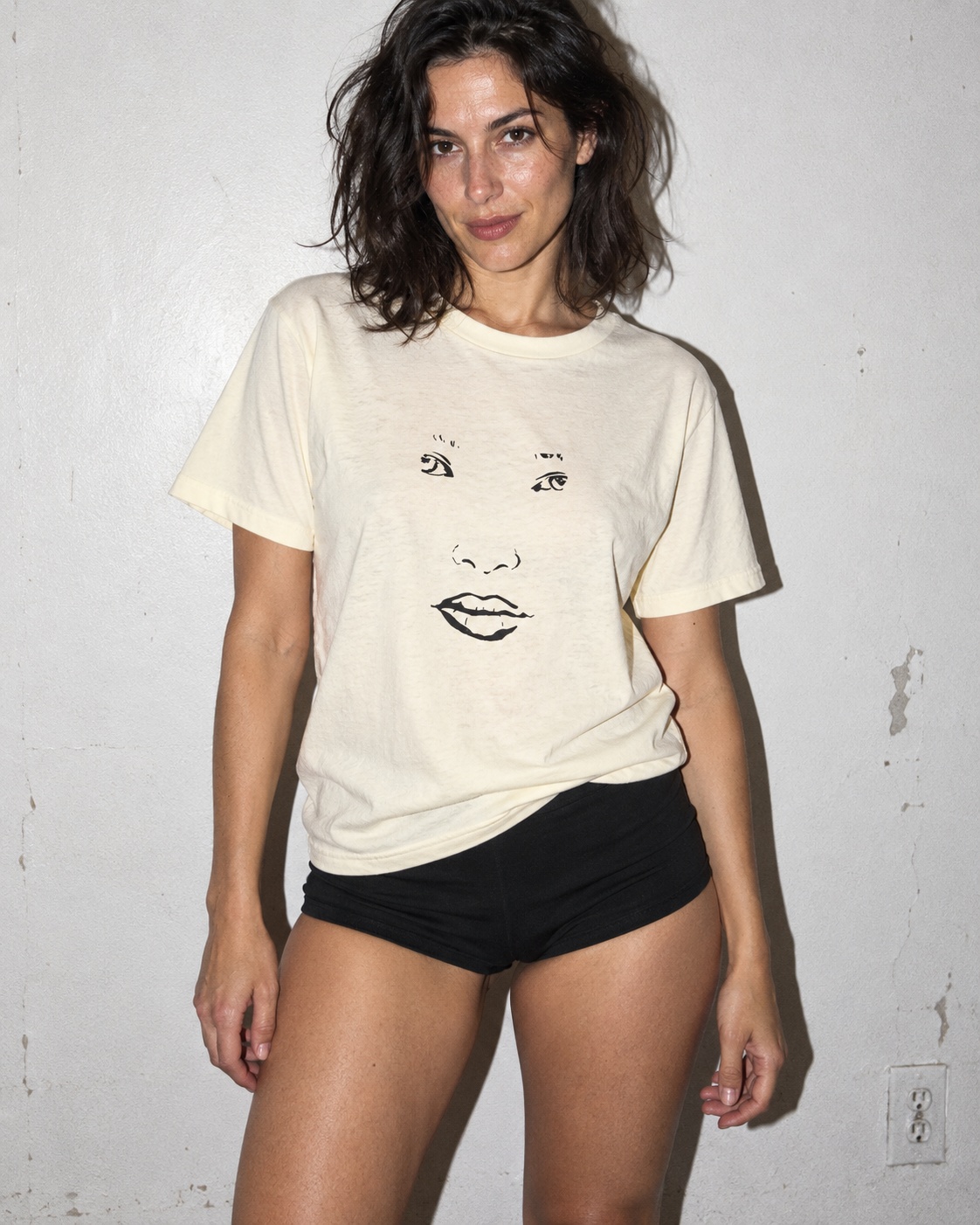 Faded Cream Face heavy tee with black face drawing, direct-flash apartment portrait